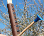 A close up of the brown coloured leather look grip on the Vah Junior Wooden Bow. A blue tipped arrow can be seen alongside it. 
