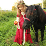 Child wearing the Vah Red Little Marian costume Dress with a cream coloured floral crown whilst feeding an apple to a pony