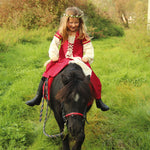 Child wearing the Vah Red Little Marian costume Dress with a cream coloured floral crown whilst riding a pony
