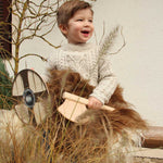 Child holding a Vah mini wooden axe in one hand and a round wooden shield in the other