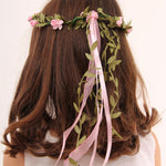 child with brown coloured hair wearing a Vah pink flower crown. View of the back of the child's head