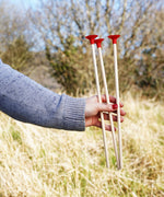 An adult holding up three red tipped safety arrows in their hand. 