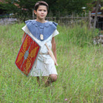 Child wearing a roman costume and carrying a Vah Roman Alexius Red Wooden Toy Shield