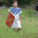 Child wearing a roman costume and carrying a Vah Roman Alexius Red Wooden Toy Shield