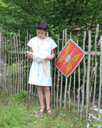 Child wearing the Vah Spartacus Roman Tunic with the red roman alexius shield placed on a fence next to them