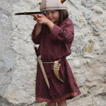 A child in full Viking costume including the Vah Viking Tunic, helmet and drinking horn. The child is playing with a cross bow.