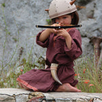 A child in full Viking costume including the Vah Viking Tunic, helmet and drinking horn. The child is playing with a cross bow.