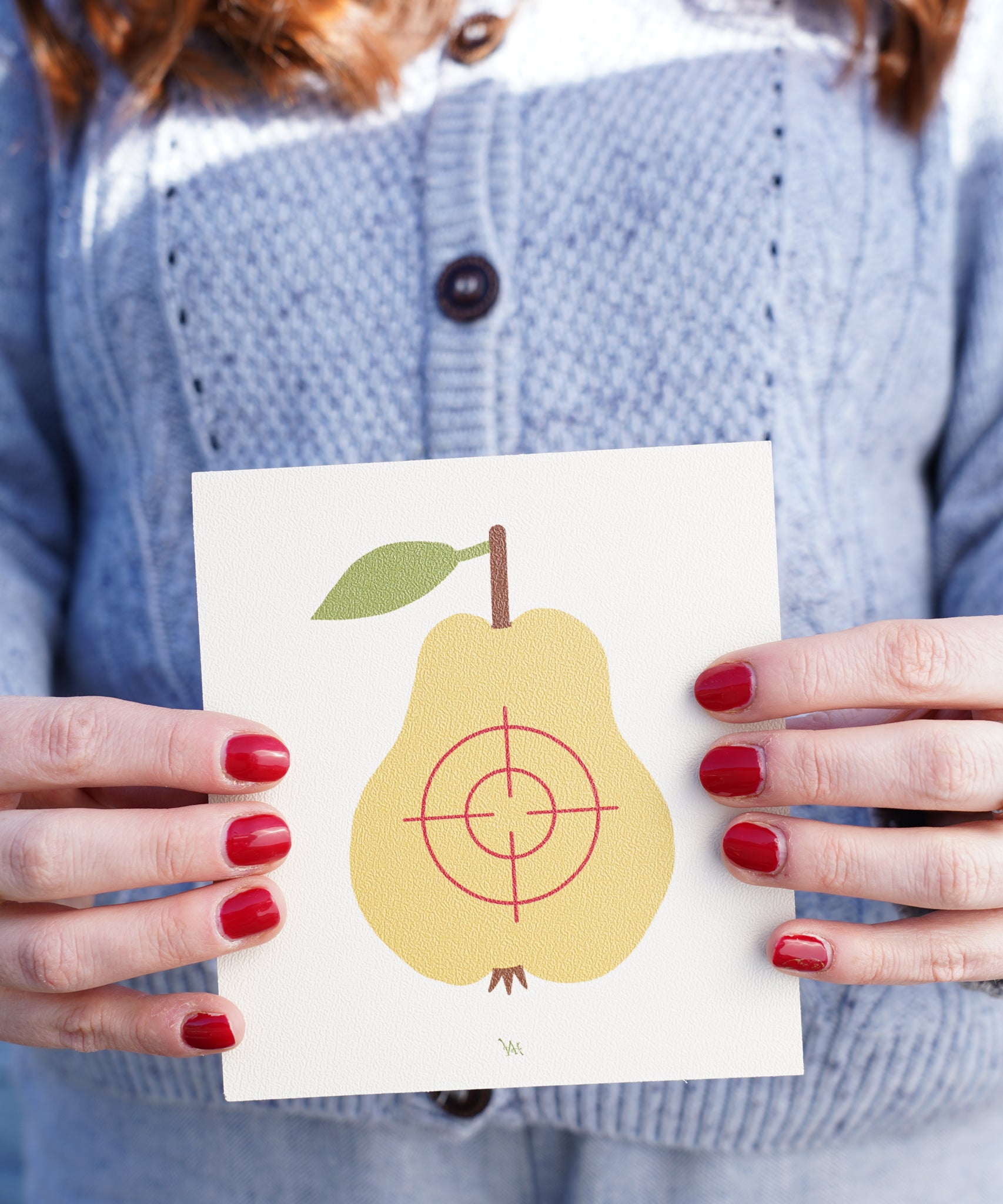 A close up of an an adult's hand holding onto the pear Vah Wooden Fruit Target.