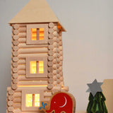 A close up of a tower built using pieces from the Walachia Vario XL Building Set 184 Pieces. Fairy lights have been placed inside the construct ion, a Babipur elephant figure has been placed besides it. This modular wooden building block system is perfect for those who enjoy a challenge. The sets are available in various sizes at Babipur. 