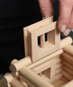 A close up of a wooden window piece being placed in a tower structure built using pieces from the Walachia Vario XL Building Set 184 Pieces.  This modular wooden building block system is perfect for those who enjoy a challenge. The sets are available in various sizes at Babipur.  
