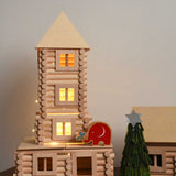 A tower built using pieces from the Walachia Vario XL Building Set 184 Pieces. There is a wooden Lanka Kade Babipur elephant figure placed on the tower with a handmade Christmas tree craft next to it.   This modular wooden building block system is perfect for those who enjoy a challenge. The sets are available in various sizes at Babipur.  