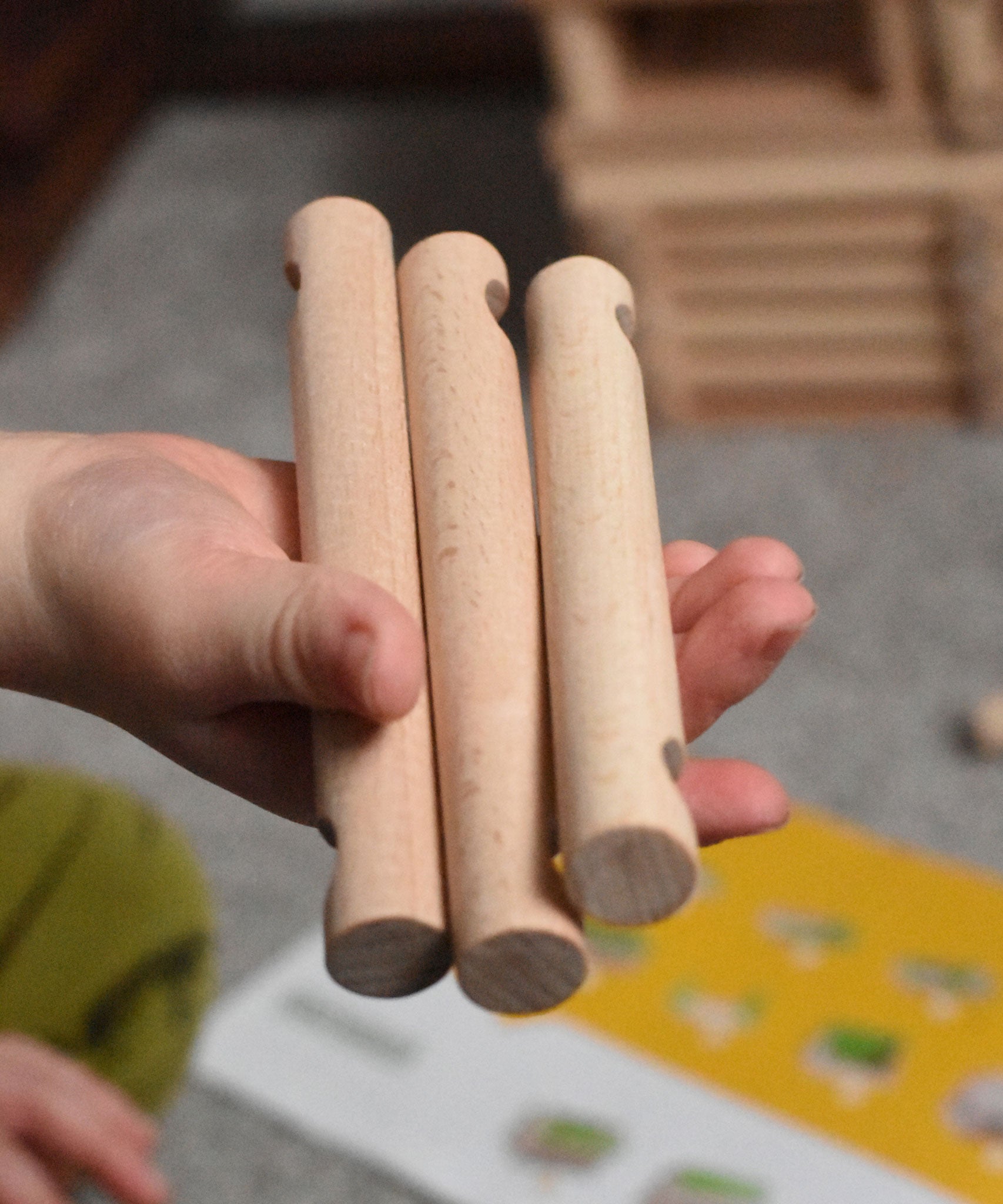 Three pieces of Walachia Vario in a child's hand. This modular wooden building block system is perfect for those who enjoy a challenge. The sets are available in various sizes at Babipur.  
