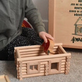 A child placing a Lanka Kade Babipur elephant figure inside a cabin created using wooden blocks from the Walachia Vario Building Sets. This modular wooden building block system is perfect for those who enjoy a challenge. The sets are available in various sizes at Babipur.  