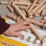 A child's hand reaching for Walachia Vario wooden log shaped blocks. This modular wooden building block system is perfect for those who enjoy a challenge. The sets are available in various sizes at Babipur.  