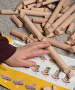 A child's hand reaching for Walachia Vario wooden log shaped blocks. This modular wooden building block system is perfect for those who enjoy a challenge. The sets are available in various sizes at Babipur.  