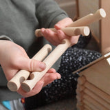 A close up of some long wooden blocks from the Walachia Vario Building Sets in a child's hands. This modular wooden building block system is perfect for those who enjoy a challenge. The sets are available in various sizes at Babipur.  
