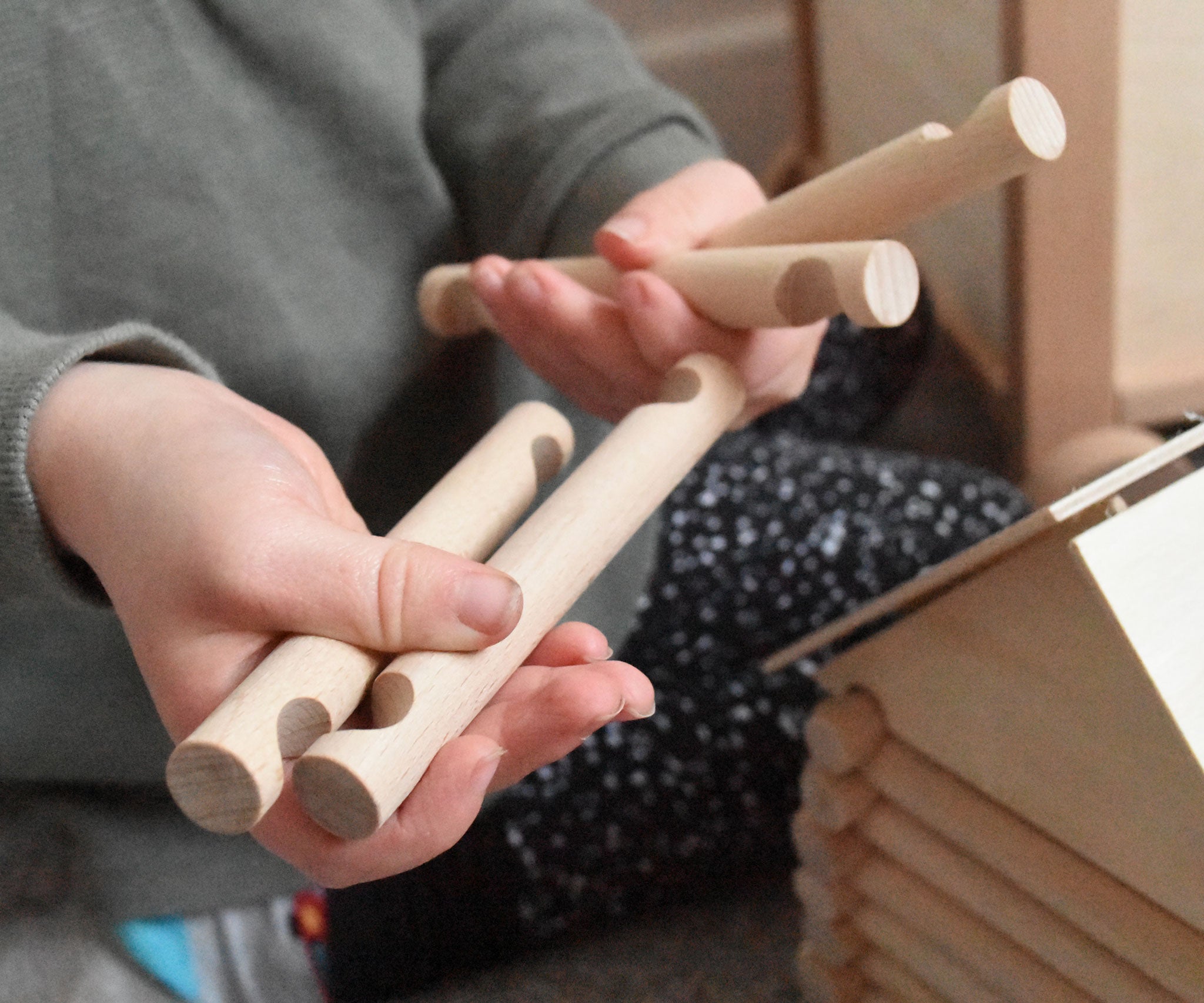 A close up of some long wooden blocks from the Walachia Vario Building Sets in a child's hands. This modular wooden building block system is perfect for those who enjoy a challenge. The sets are available in various sizes at Babipur.  