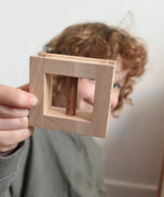 A child holding up a wooden window from the Walachia Vario Building Sets up to the camera. This modular wooden building block system is perfect for those who enjoy a challenge. The sets are available in various sizes at Babipur.  