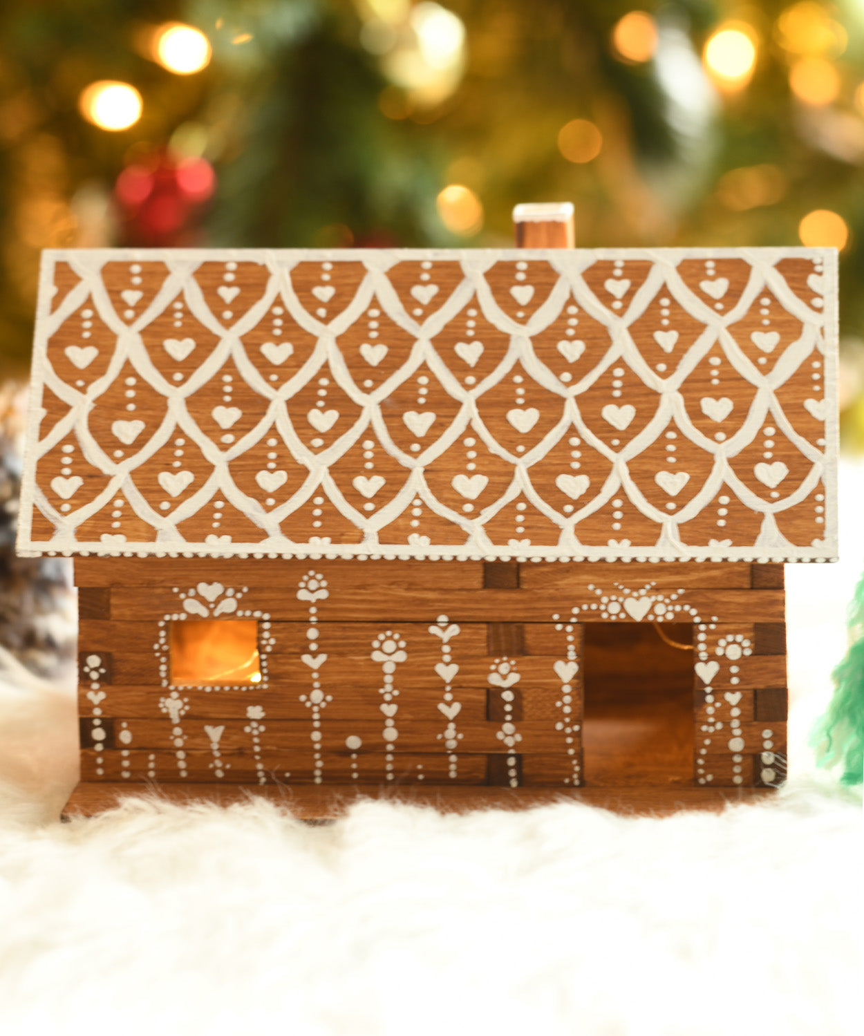 A beautifully festive decorated WALACHIA log cabin house. There are little fairy lights in the house creating a lovely warm glow inside