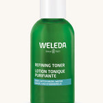 A green Weleda bottle for the refining toner on a cream background
