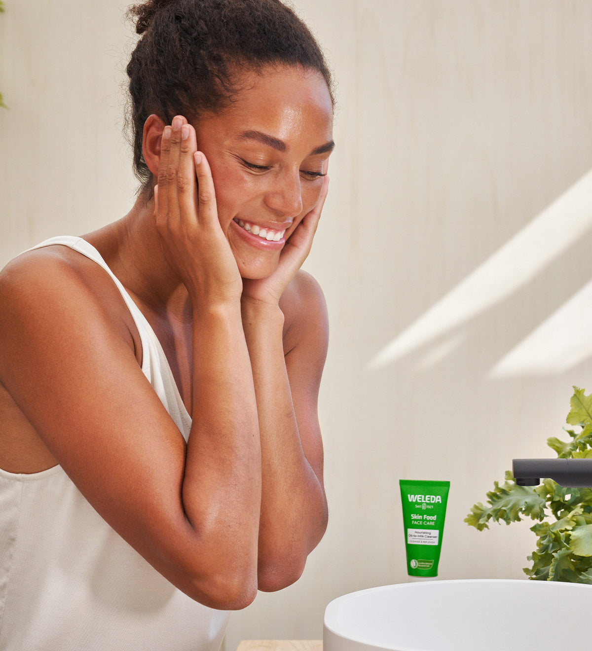 A close up photo of a person washing their face with the Weleda Nourishing face balm