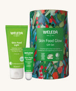 Weleda Skin Food Glow Gift Set. The contents, Skin Food Light and Skin Food Lip Balm are shown next to the cardboard tube gift packaging. 