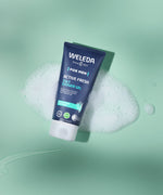 Weleda Men’s Active Fresh 3 in 1 Shower Gel tube resting on green foam with bubbles.