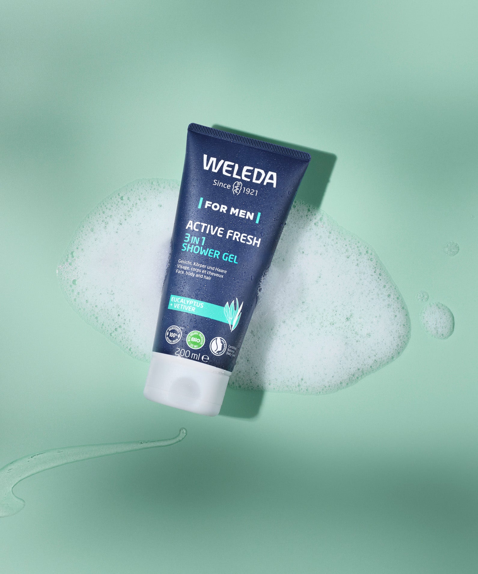 Weleda Men’s Active Fresh 3 in 1 Shower Gel tube resting on green foam with bubbles.