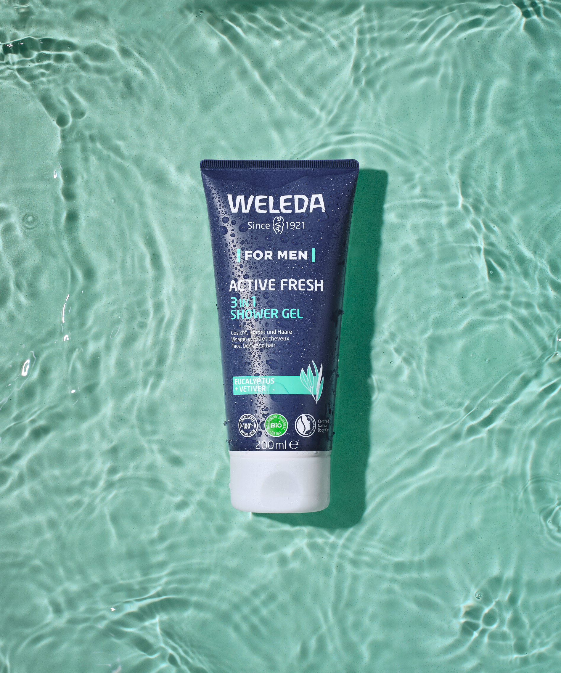 Tube of Weleda Men’s Active Fresh 3 in 1 Shower Gel floating on rippled green water.