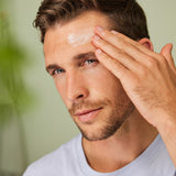Man applying Weleda Men’s Organic Moisture Cream to his forehead in a bathroom setting.