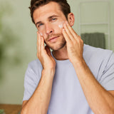 Man massaging Weleda Men’s Moisture Cream natural skincare onto his cheeks with both hands.
