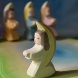 A white coloured Ostheimer little angel placed on a wooden pond scene piece. This wooden figure is part of a large range of expertly hand crafted, Waldorf inspired, wooden toys here at Babipur. 