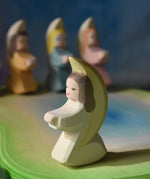 A white coloured Ostheimer little angel placed on a wooden pond scene piece. This wooden figure is part of a large range of expertly hand crafted, Waldorf inspired, wooden toys here at Babipur. 