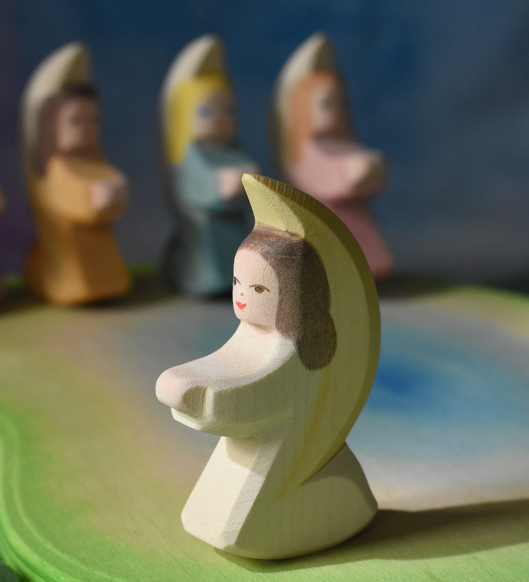 A white coloured Ostheimer little angel placed on a wooden pond scene piece. This wooden figure is part of a large range of expertly hand crafted, Waldorf inspired, wooden toys here at Babipur. 