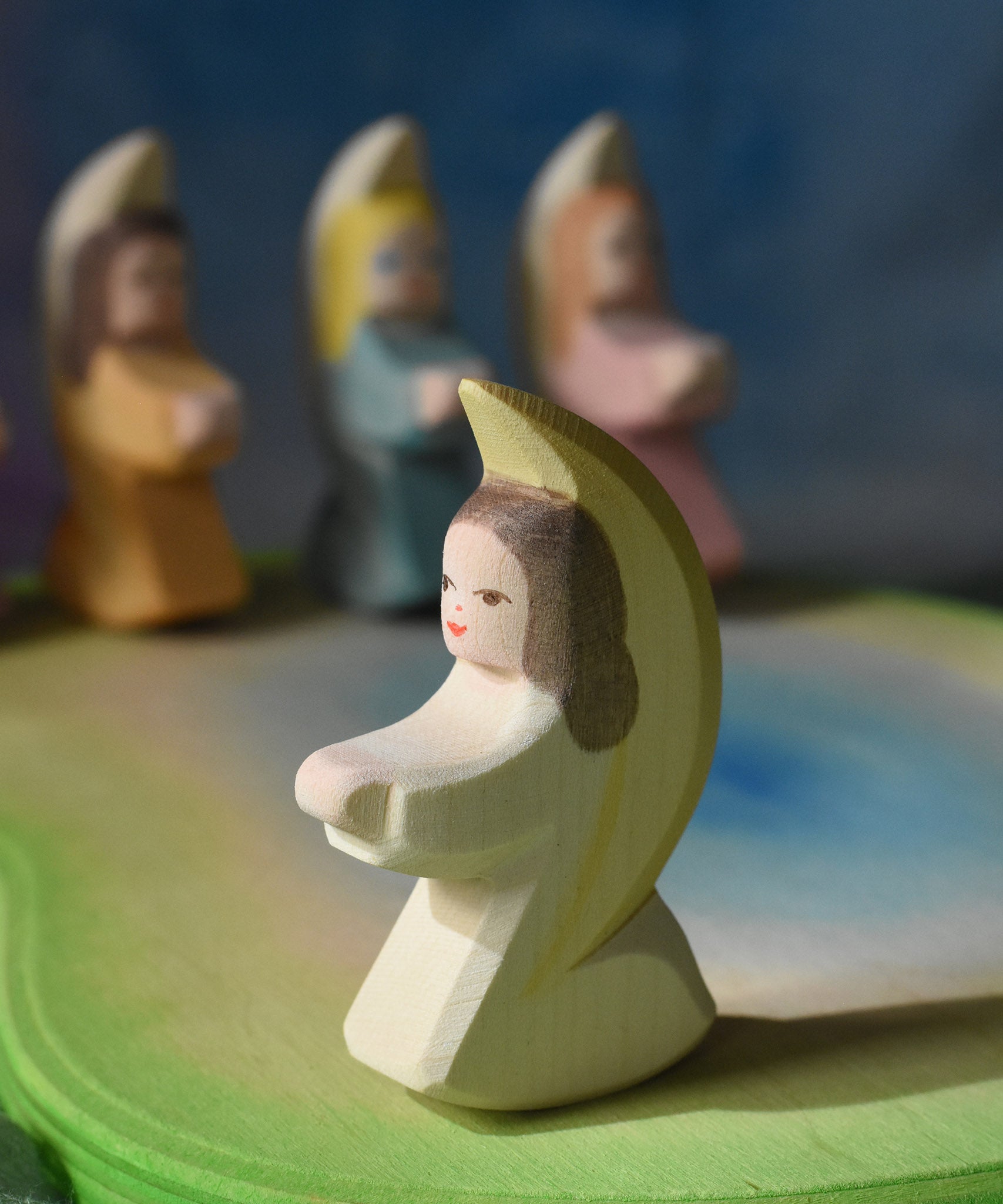 A white coloured Ostheimer little angel placed on a wooden pond scene piece. This wooden figure is part of a large range of expertly hand crafted, Waldorf inspired, wooden toys here at Babipur. 
