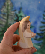 A white coloured Ostheimer little angel held in an adult's hand to show scale. This wooden figure is part of a large range of expertly hand crafted, Waldorf inspired, wooden toys here at Babipur. 