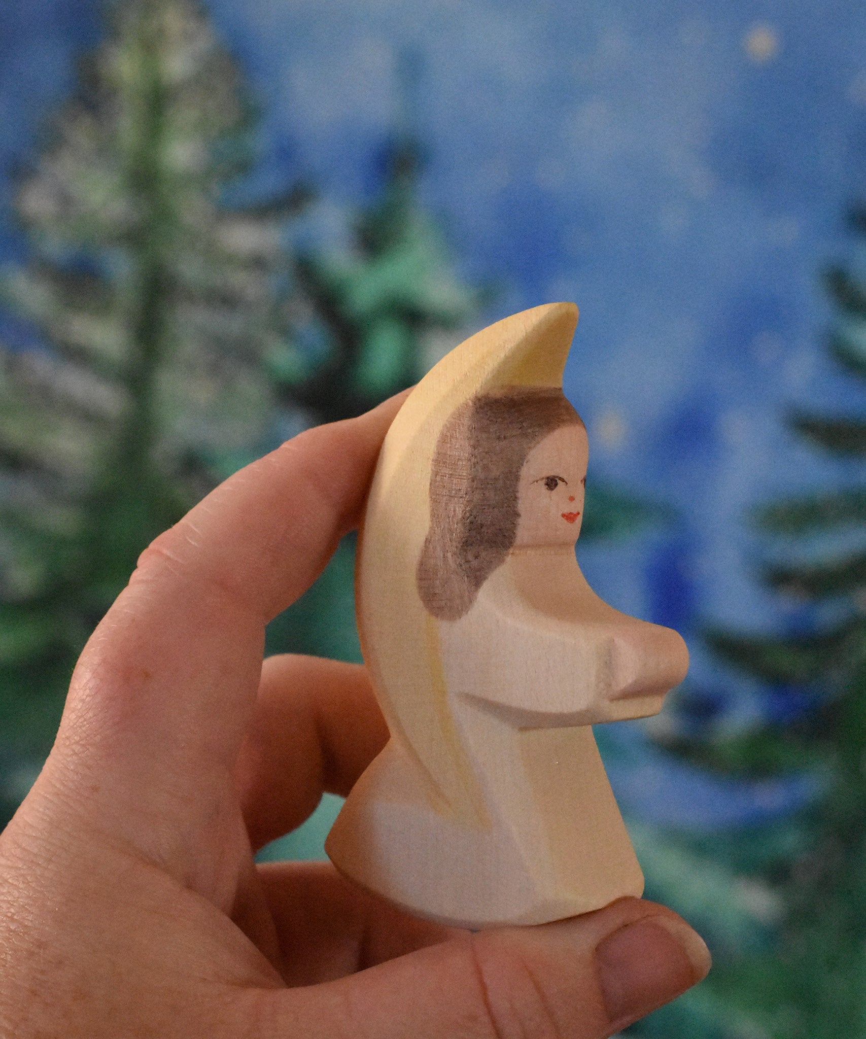 A white coloured Ostheimer little angel held in an adult's hand to show scale. This wooden figure is part of a large range of expertly hand crafted, Waldorf inspired, wooden toys here at Babipur. 