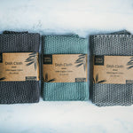 3 Wild and Stone organic cotton dish cloths laid out in a line on a white marble background