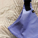 A close up of the Wildride lavender toddler  carrier showing the strap details between the seat. 