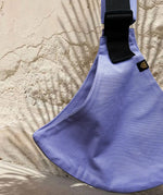 A close up of the Wildride lavender toddler  carrier showing the strap details between the seat. 