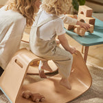 Child sat on top of the Wobbel beech wood Big Up balancing box in front of a blue table