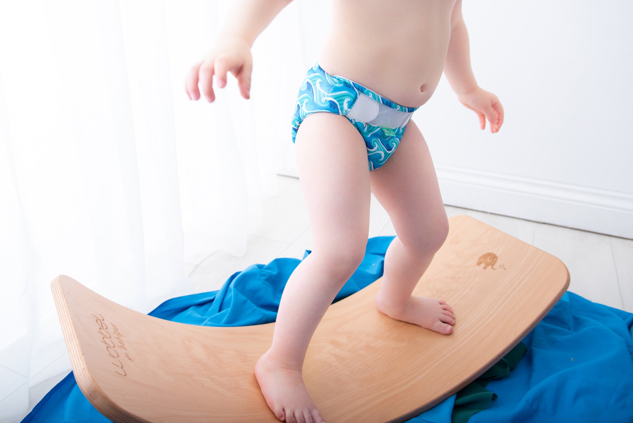Toddler balancing on the Babipur edition Wobbel Original beech balance board without felt in a bright playroom.