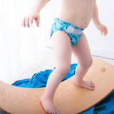 Toddler balancing on the Babipur edition Wobbel Original beech balance board without felt in a bright playroom.