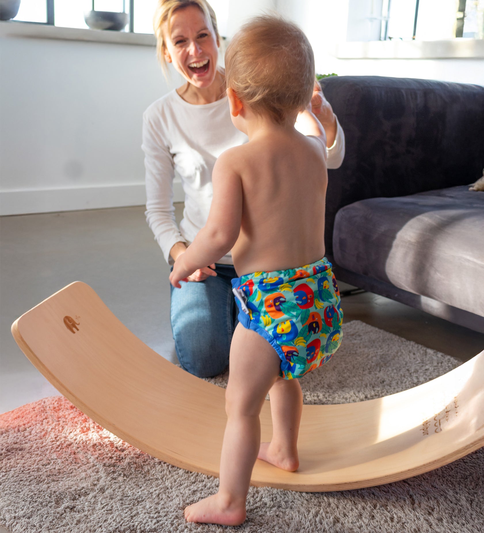 Toddler practising balance on the Babipur edition Wobbel Original beech board with no felt while a parent watches.