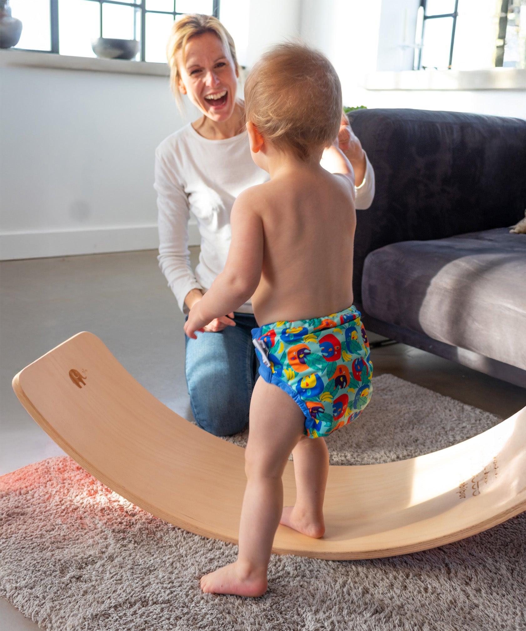 Toddler practising balance on the Babipur edition Wobbel Original beech board with no felt while a parent watches.