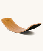 Wobbel Original bamboo balance board with black wool felt backing shown in curved position.