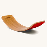 Wobbel Original bamboo balance board with red wool felt backing on a plain background.
