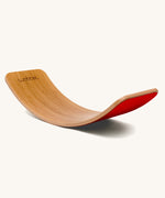 Wobbel Original bamboo balance board with red wool felt backing on a plain background.