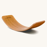 Wobbel Original bamboo balance board with rust wool felt backing on a plain background.
