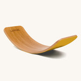 Wobbel Original bamboo balance board with yellow natural wool felt backing shown in arch position.